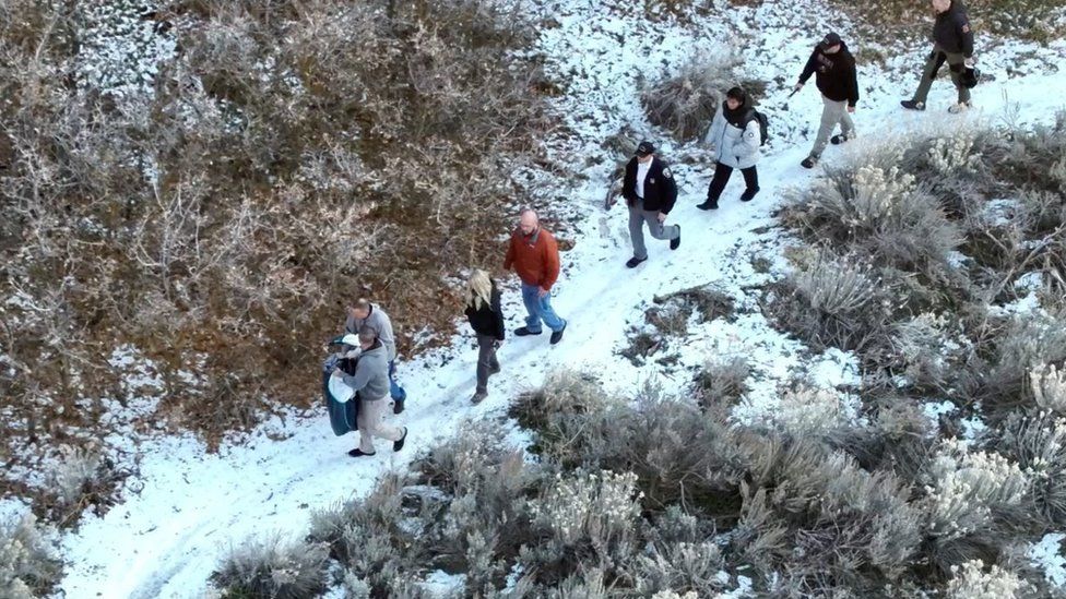 Kai and rescuers walk along a snow-covered path