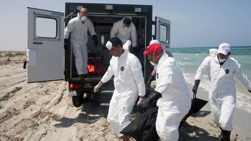 Workers for the Red Crescent carry the body of a dead migrant at the waterfront in Zuwara