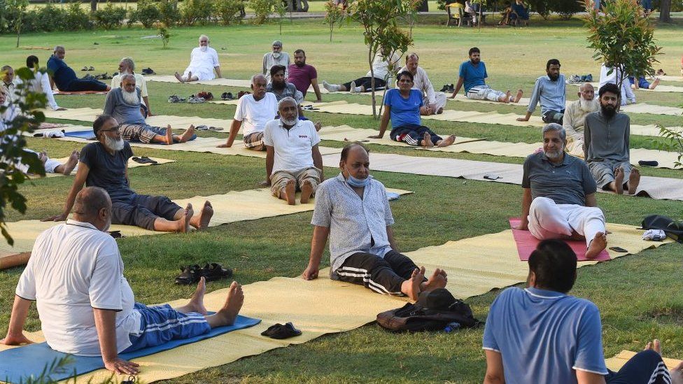 Люди практикуют йогу в преддверии Международного дня йоги в Лахоре 20 июня 2021 года.