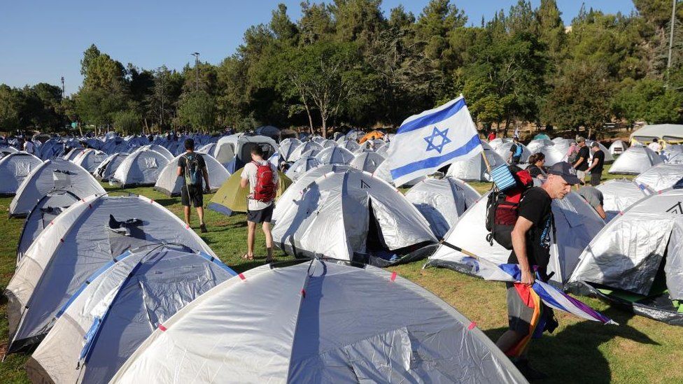 Anti-government protesters stand among tents after spending the night in a tent camp at Sacher Park, near the Israeli Knesset, following a four-day protest march to Jerusalem against the government's planned justice system reform, in Jerusalem, 23 July 2023.