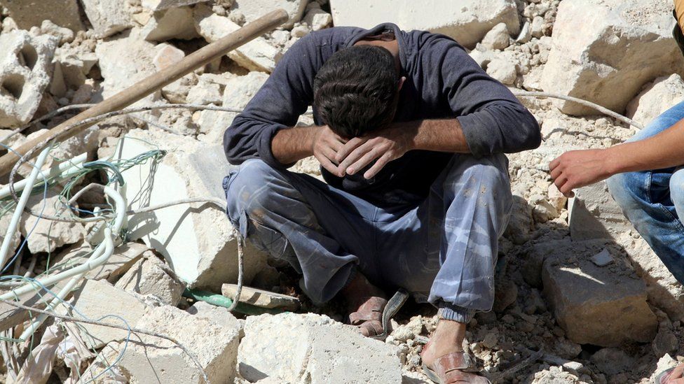 A man sits on rubble after learning of the deaths of relatives in a reported government air strike in the rebel-held Qaterji district of Aleppo (11 October 2016)