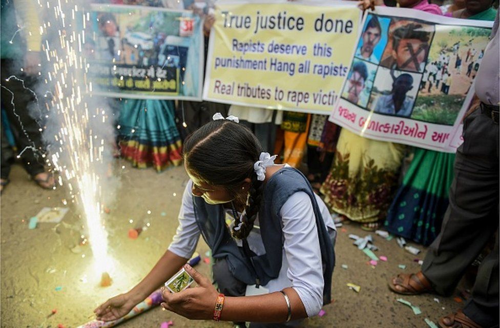 Школьница в Ахмедабаде зажигает петарды после того, как полиция убила четырех подозреваемых в групповом изнасиловании и убийстве в Хайдарабаде 6 декабря 2019 г.