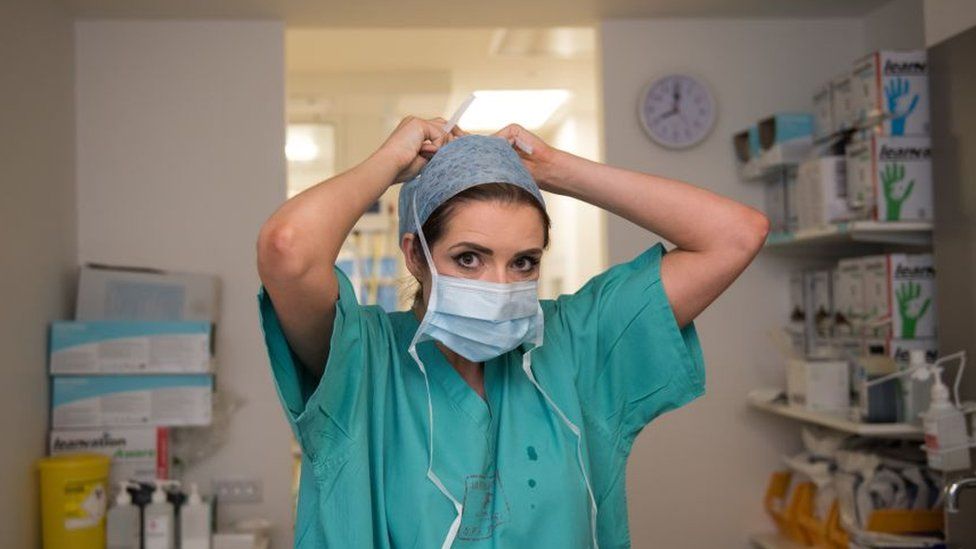 Nurse putting on a surgical mask