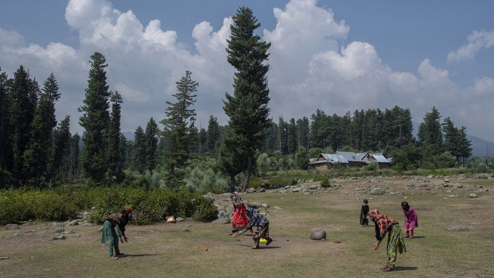 A group of girls play cricket during break.