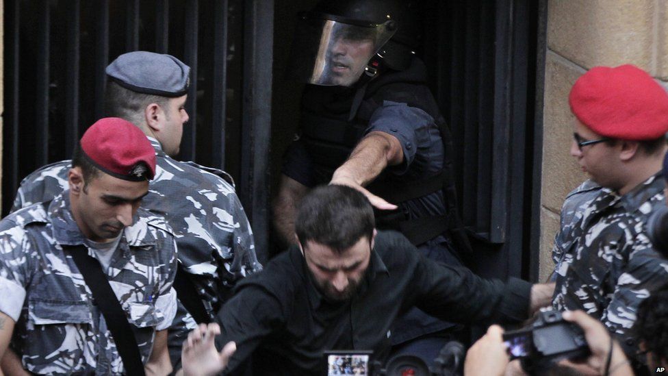 Lebanese riot police eject a protester from the environment ministry