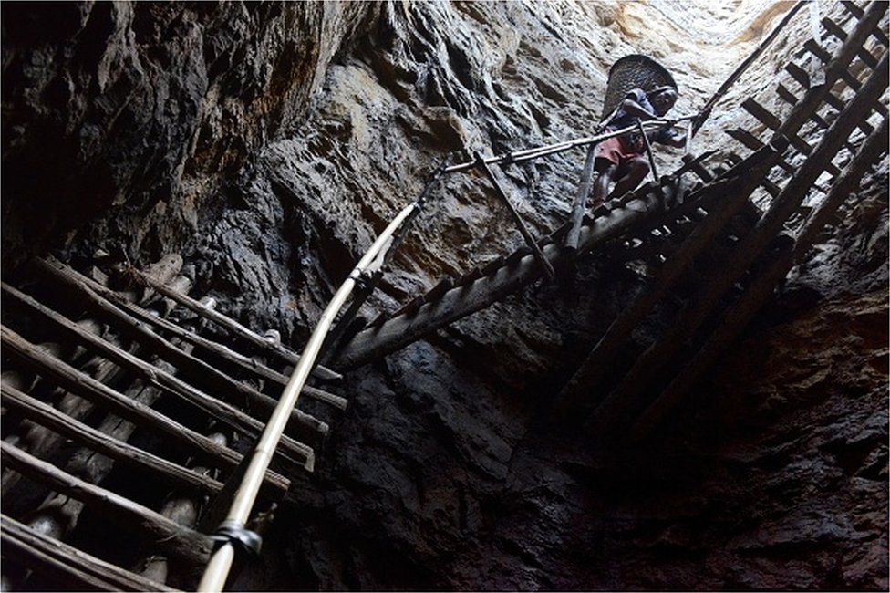 In this photograph taken on January 31, 2013, a miner slowly carries a heavy load of wet coal on a basket hundreds of feet up on wooden slats that brace the sides of a deep coal mine shaft near Rimbay village in the Indian northeastern state of Meghalaya. Thousands of private mines employ slim men and boys that will fit in thin holes branching out from deep shafts dug out from the ground in the East Jaintia Hills in Northeastern Indian state of Meghalaya