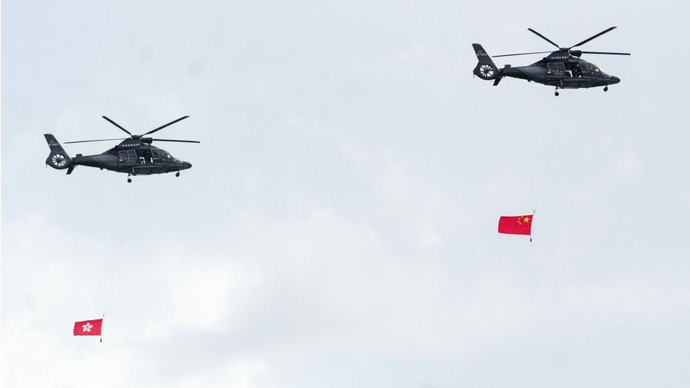 Military helicopters perform a fly by with the Chinese (R) and Hong Kong (L) flags in Hong Kong on July 1, 2016