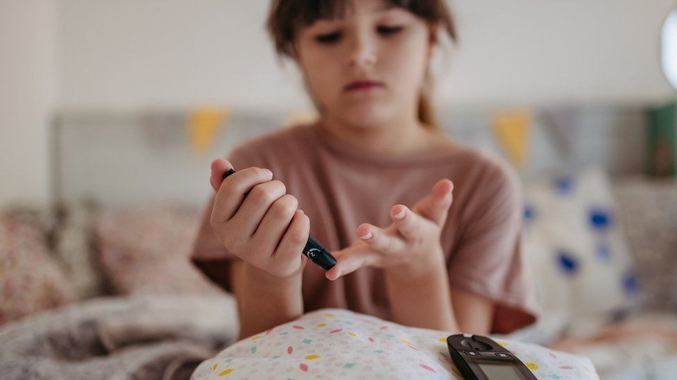 Diabetic girl taking finger stick test at home to check blood sugar level throughout the day