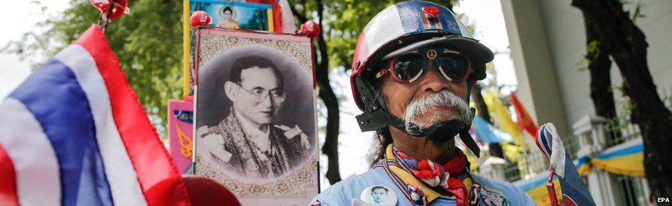 Thai cyclist Add, 67, pushes his bike past a photograph of Thai King Bhumibol Adulyadej before taking part in the "Bike for Mom" mass bicycle ride campaign in Bangkok, Thailand, on Sunday