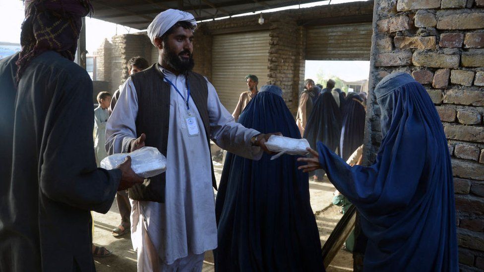 A burka-clad woman receives a food donation from the Afterlife foundation during Islam's Holy fasting month of Ramadan in Kandahar on April 27, 2022.