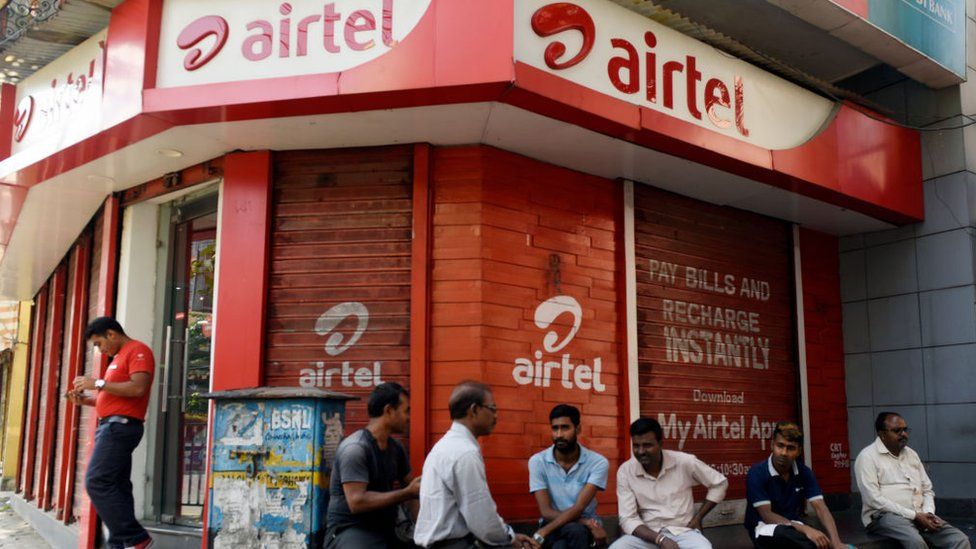 Men sit in front of Airtel store in Kolkata