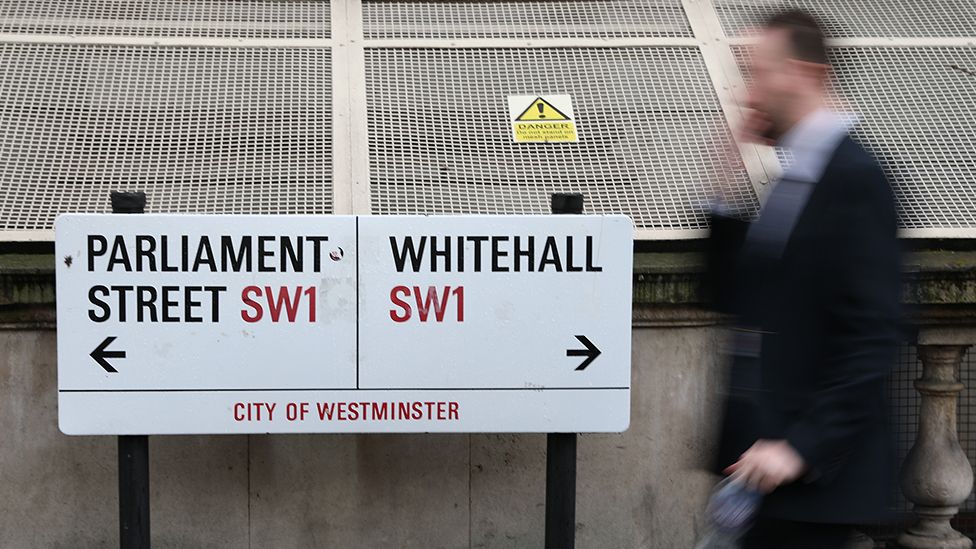 Civil servant walks past Whitehall sign