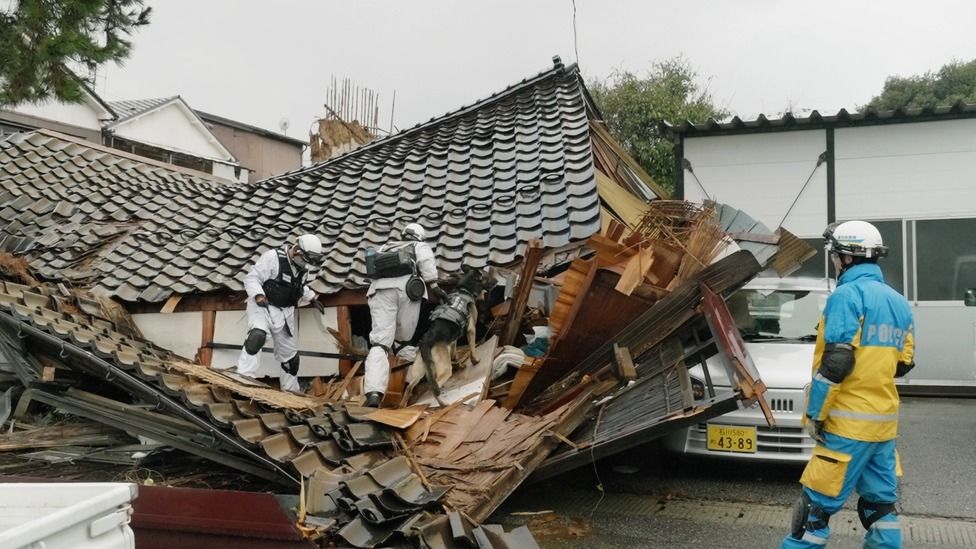 Rescue workers look through rubble of a collapsed house