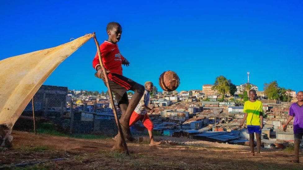 Кенийский мальчик в футболке «Манчестер Юнайтед» играет в футбол в Найроби