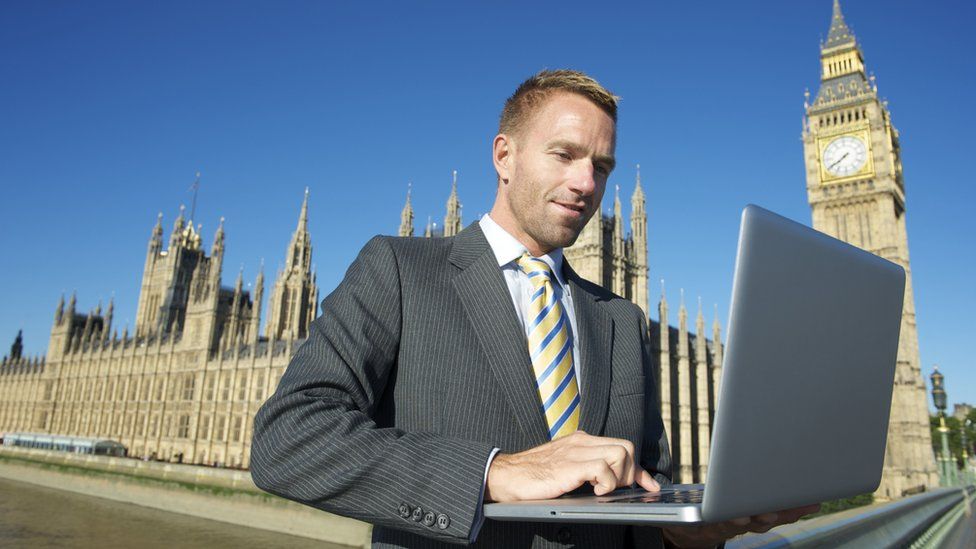 Man uses laptop on Parliament Bridge outside Westminster