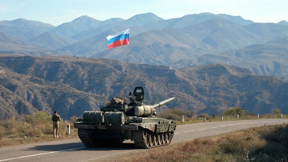 A service member of the Russian peacekeeping troops walks near a tank near the border with Armenia