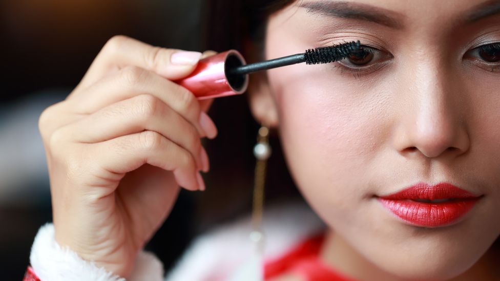 A woman applies mascara to her eyelashes
