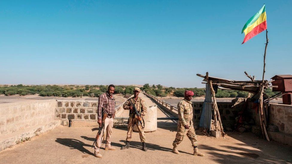 Two members of the Amhara Special Forces with a member of the Amhara militia (L) stand at the border crossing with Eritrea where an Imperial Ethiopian flag waves, in Humera, Ethiopia, on November 22, 2020.