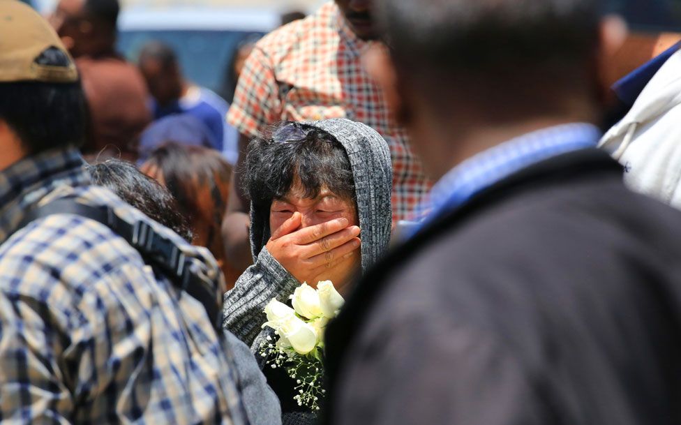A woman holding flowers cries for a Chinese victim during a memorial service at the crash site of Ethiopian Airlines flight ET302 on March 13, 2019 in Bishoftu, Ethiopia.