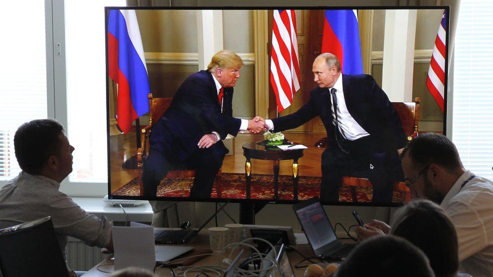 Russian journalists watch Mr Trump shake hands with Mr Putin (R) in July 2018