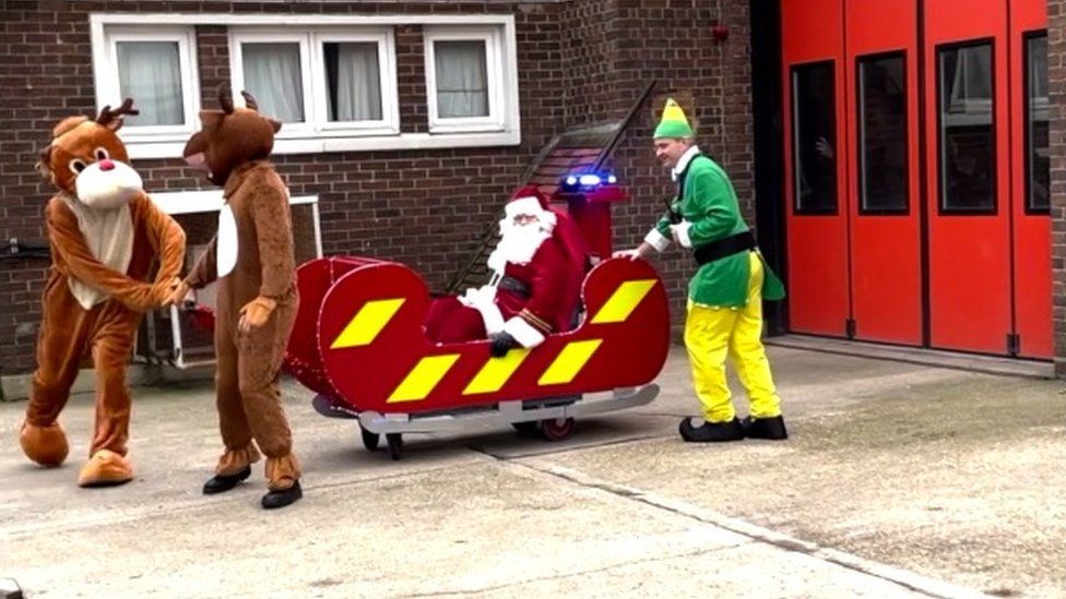 Santa being pulled by reindeer in a fire engine sleigh