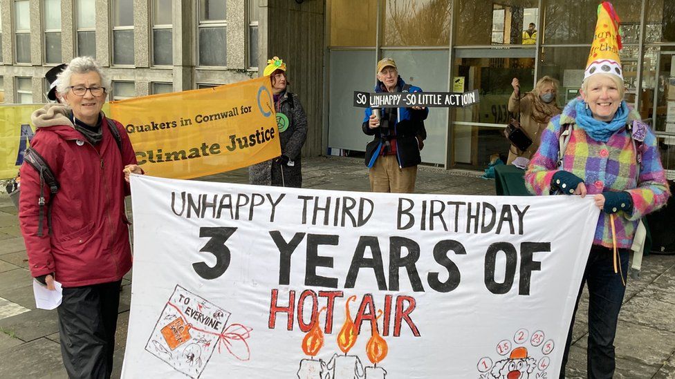 Two protesters with '3 years of hot air' banner