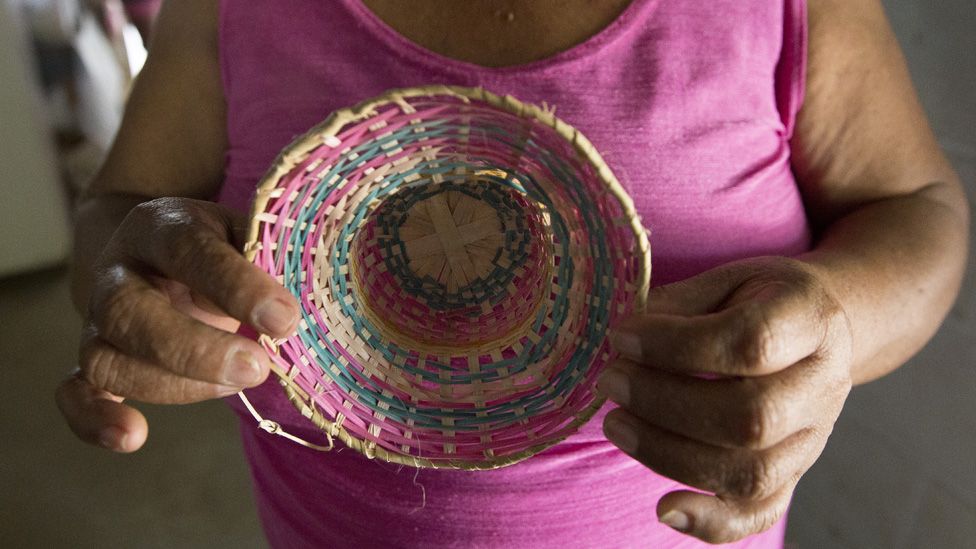 Elvia Bautista, de 53 años, de Córdoba, Colombia, muestra un pequeño sombrero hecho de fibras de las plantas de su casa.