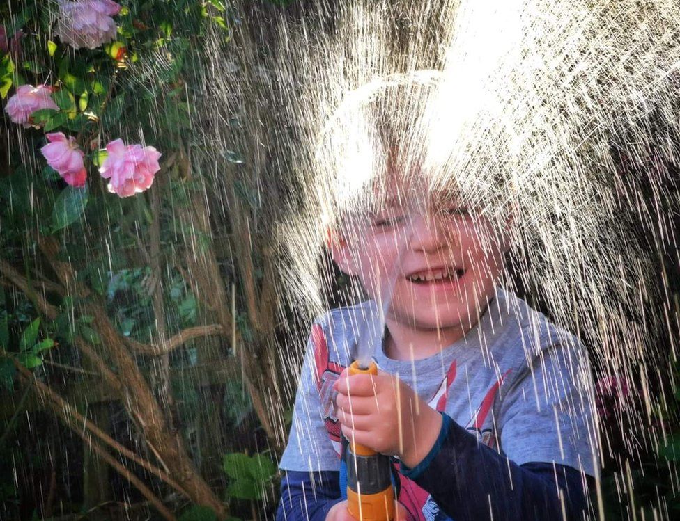 A boy playing with water from a hose-pipe
