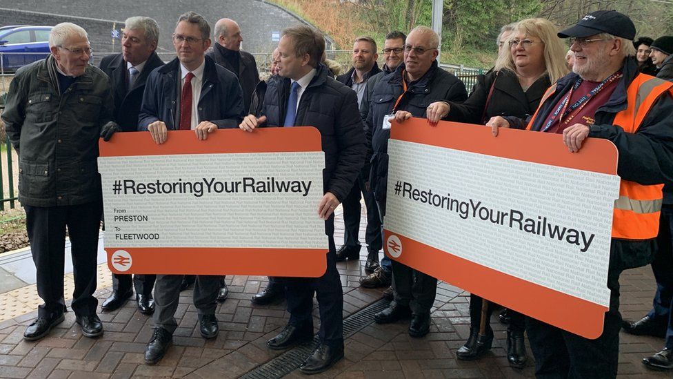 Grant Shapps and people holding giant rail tickets on the platform at Fleetwood