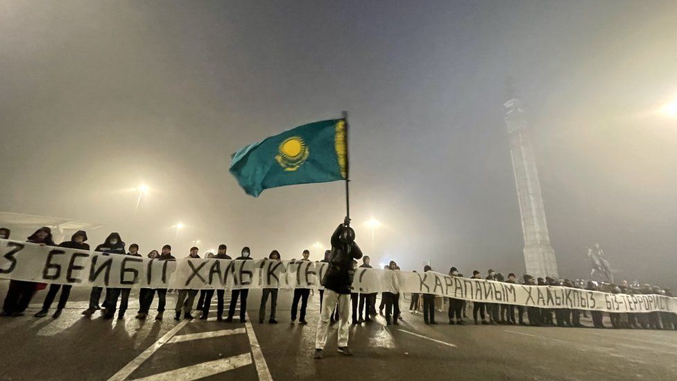 Protesters on Almaty's main square hold a banner saying "we are not terrorists" on 6 January shortly before the shooting