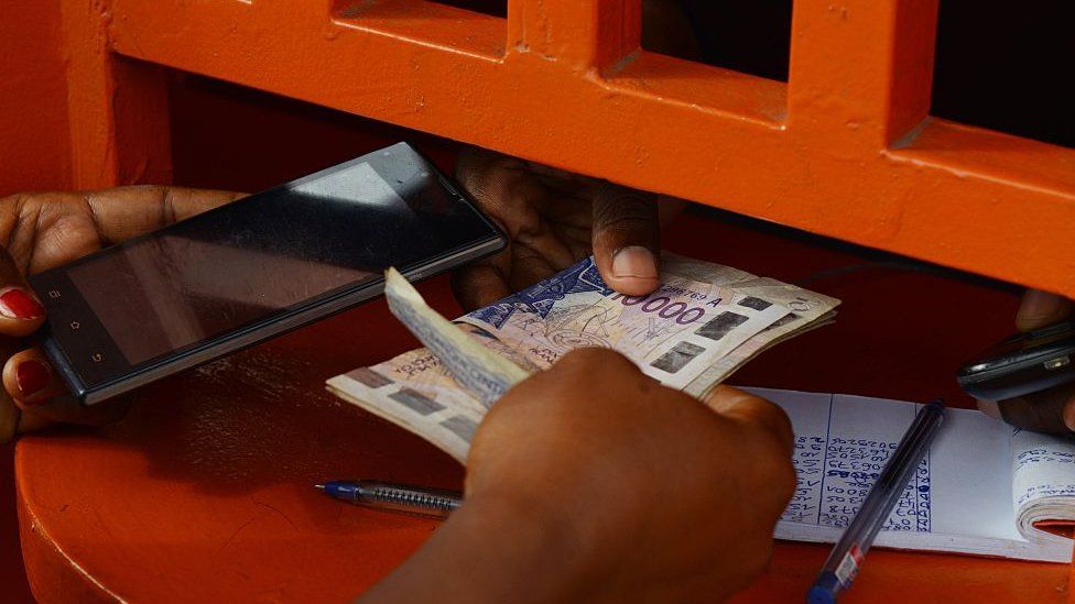 A woman withdraws money at an Orange Money cashier booth