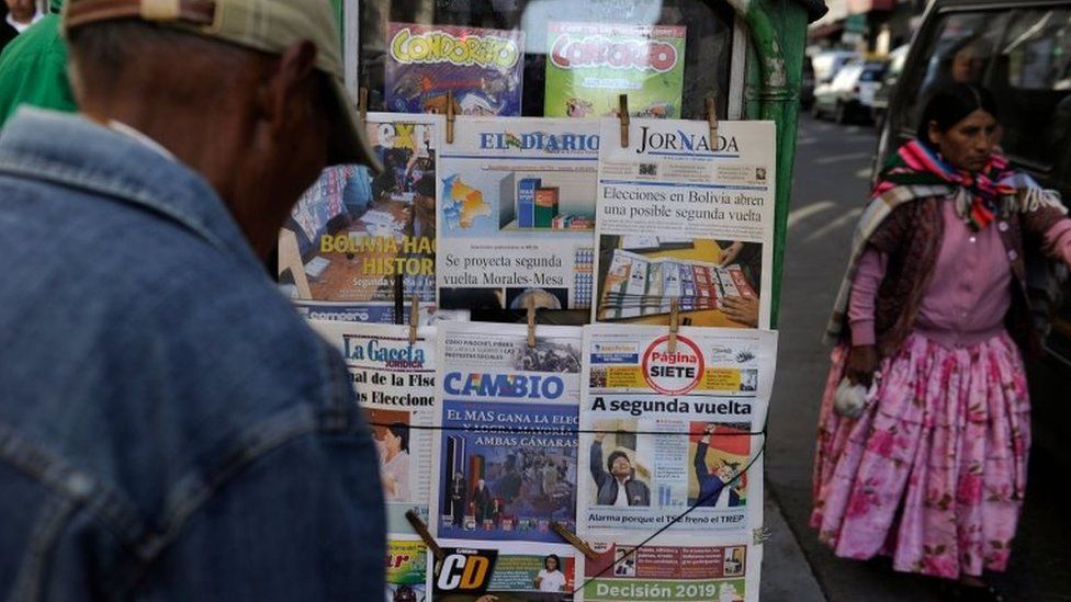 People read front pages of newspapers after the presidential election, in La Paz, Bolivia, on October 21, 201