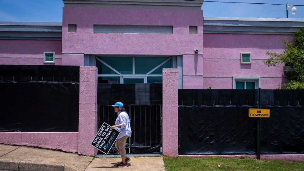 An anti-abortion protestor moves a sign from outside at the Jackson Womens Health Organization also known as the The Pink House in Jackson, MS on June 7, 2022