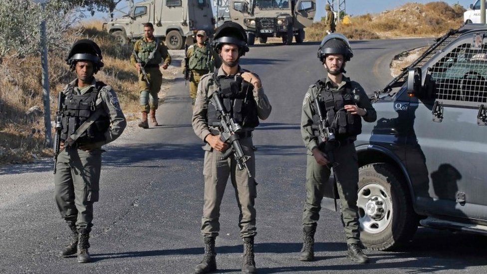Israeli soldiers stand guard next to the site where the body of an Israeli soldier was found