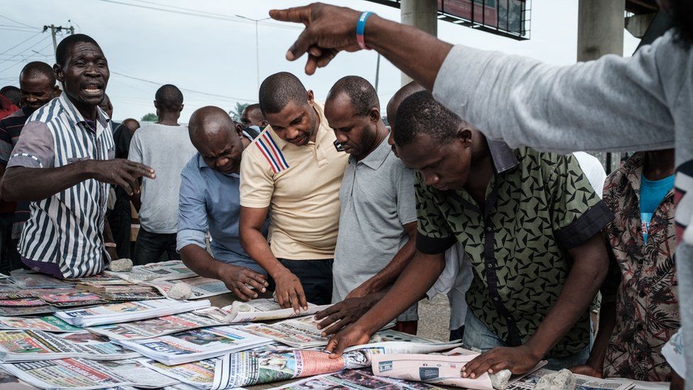 Nigerians at a newspaper stand