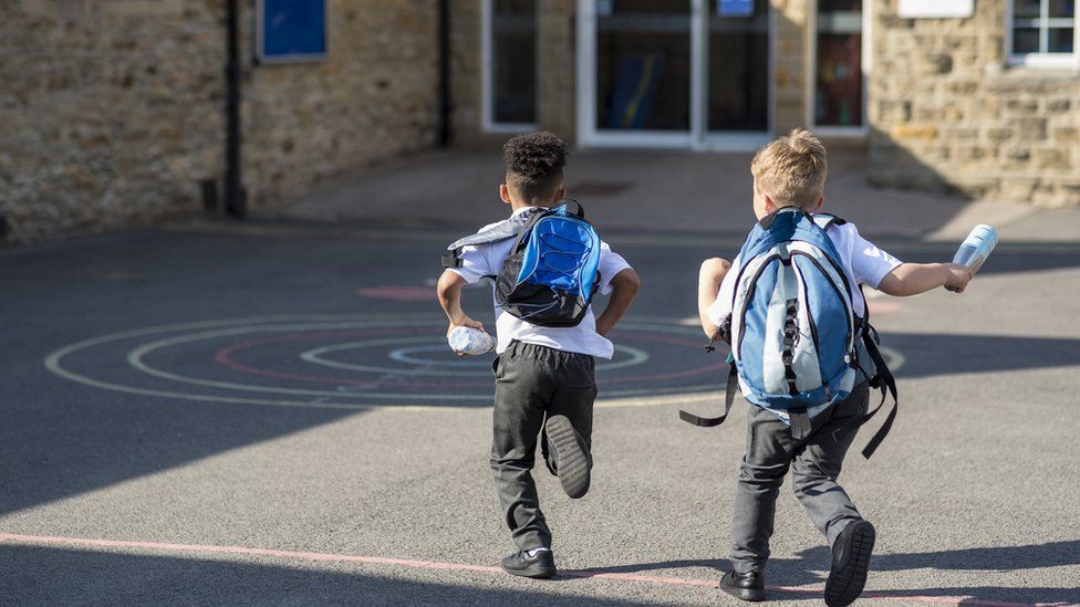 Two primary-aged children running into school
