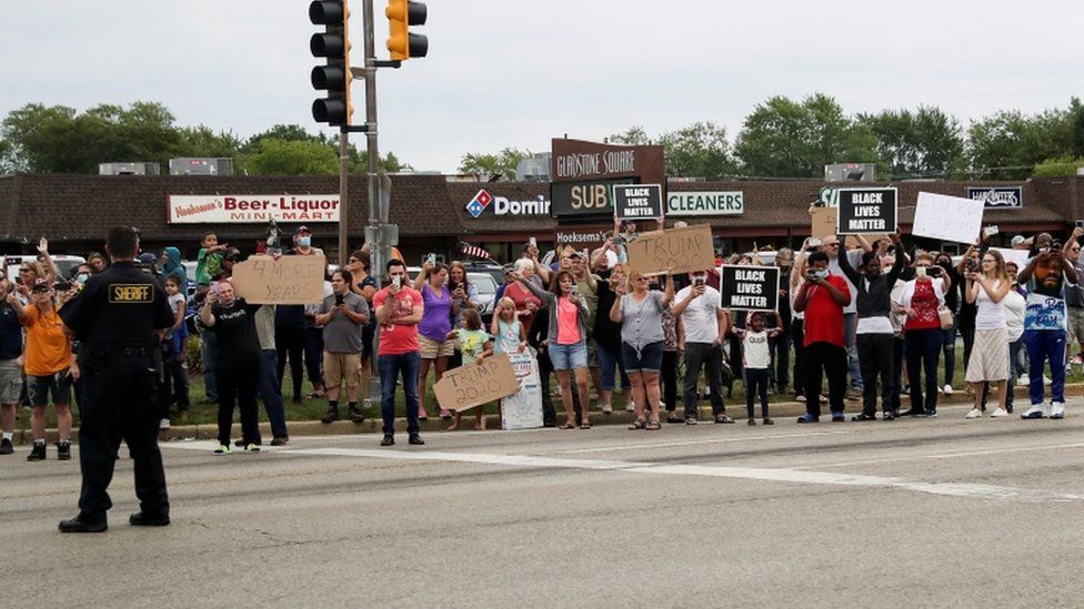 A mix of protesters and supporters line the road as the motorcade of U.S. President Donald Trump passes by on his way to Kenosha Wisconsin