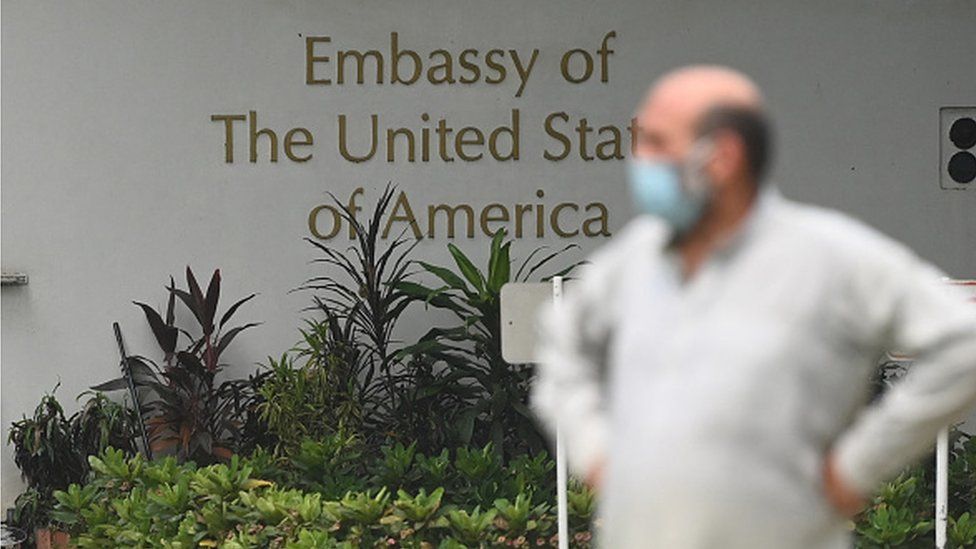 Мужчина стоит у посольства США в Нью-Дели