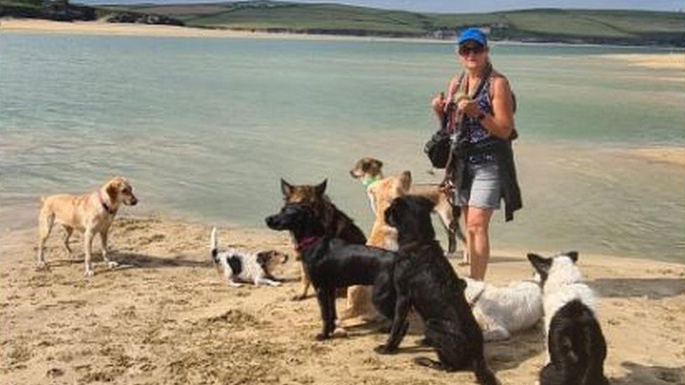Hilary Holley standing on a beach with her nine dogs