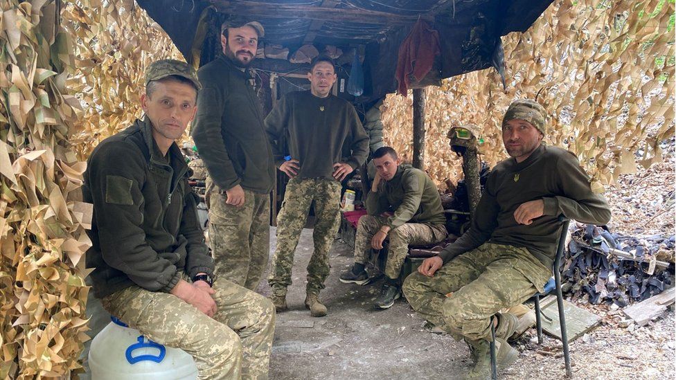 Ukrainian gunners under camouflage netting