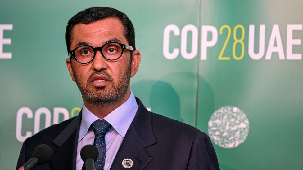 Sultan al-Jaber gives a speech with COP28 banners in the background.