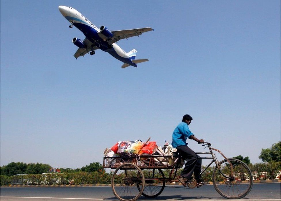 An IndiGo Airlines aircraft prepares to land as a man paddles his cycle rickshaw in Ahmedabad, India, October 26, 2015