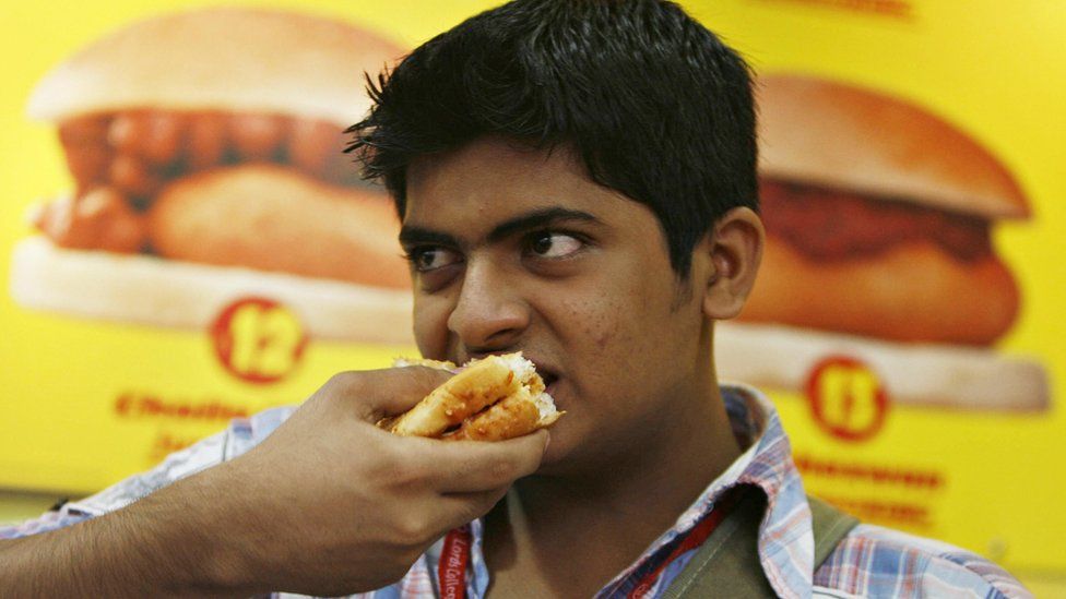 An Indian youth eats the popular food snack vada pav at a Jumbo King food outlet in Mumbai on September 20, 2008.