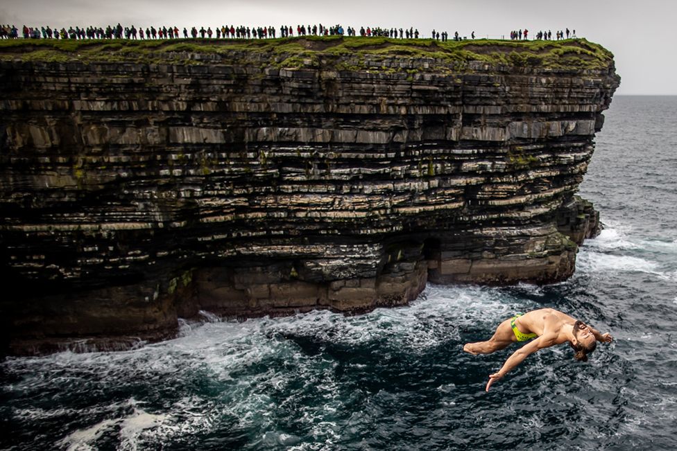 Каталин Преда из Румынии прыгает с 27-метровой платформы на Мировой серии Red Bull Cliff Diving, Даунпатрик-Хед, Ирландия, сентябрь 2021 г.