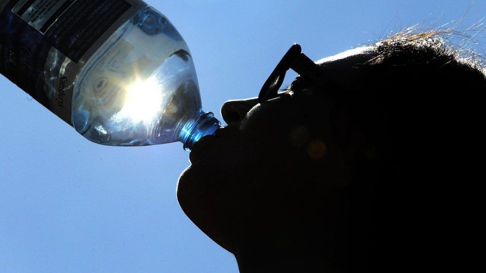 A person drinks water during hot weather