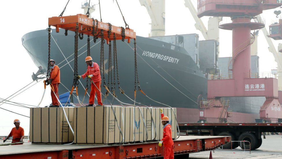 Workers load boxes onto a ship at Lianyungang Port.