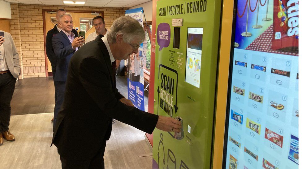 First Minister Mark Drakeford using a bottle deposit bank in Brecon leisure centre