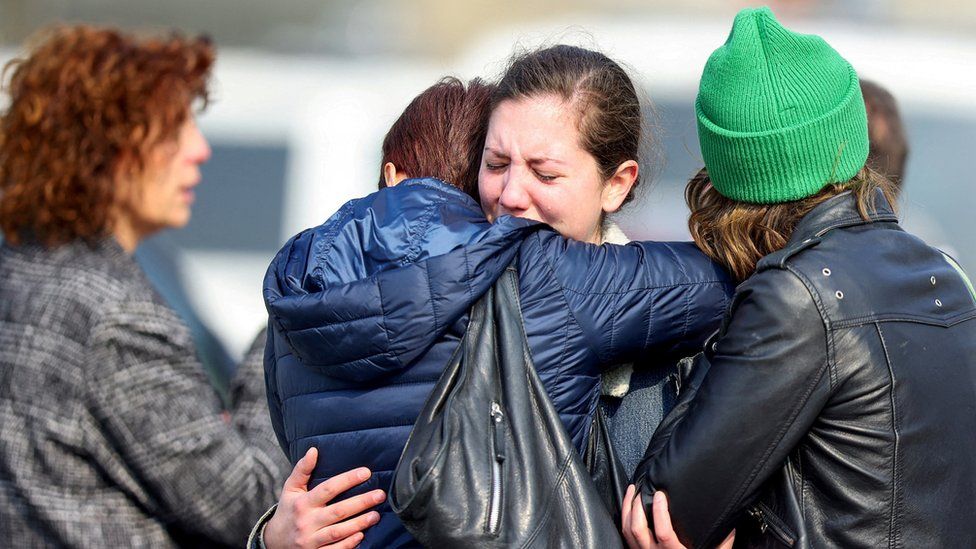 Women react as they embrace each other after the attack