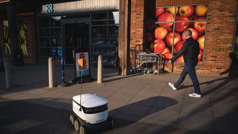 Человек и автономный робот перед супермаркетами Co-op