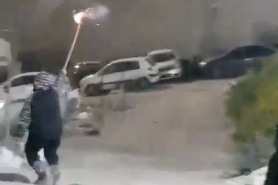 Rami Hamdan Al-Halhouli, 12, holds a firework aloft moments before being shot by Israeli police.